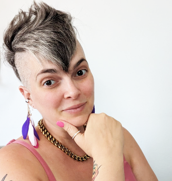 head and shoulder portrait of short heaired Melissa wearing a strappy top and feather earings