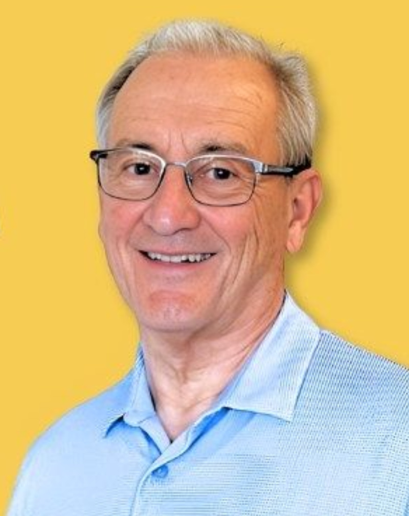 head and shoulder portrait of a smiling senior man wearing glasses and a light blue shirt